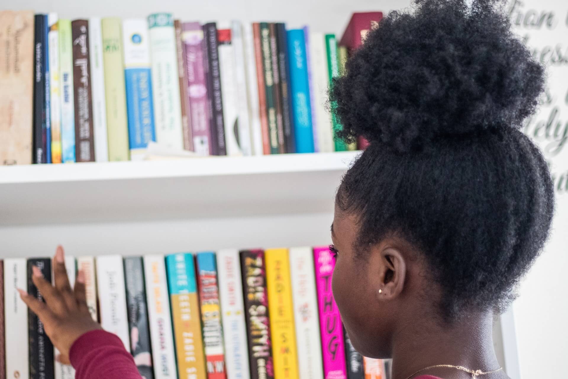 femme aux cheveux frisés et crépus avec un afropuff regardant une bibliothèque